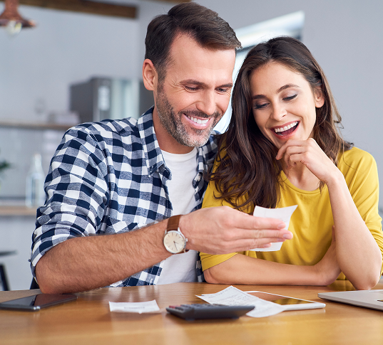 Uśmiechnięta para przeglądająca rachunki przy stole w domu